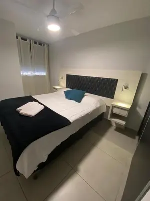 a bedroom with a large bed with a blue pillow at LitStay Brasil con cochera, pileta y asadores in Cordoba