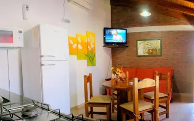 a kitchen with a table and a television on a wall at Complejo Sol in Villa Carlos Paz