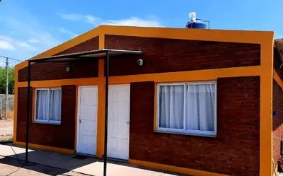 a red brick building with two white garage doors at Ruta 20 HOUSE Quines in Quines