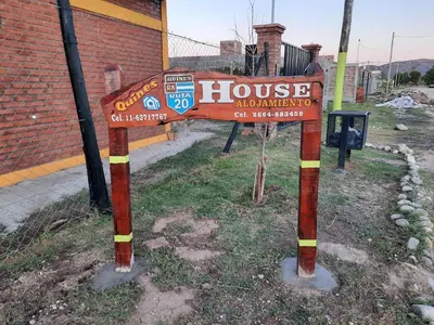 a sign in the grass in front of a building at Ruta 20 HOUSE Quines in Quines