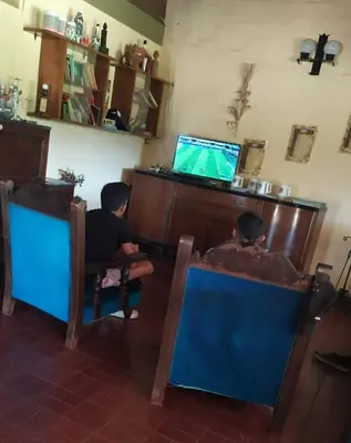 two boys sitting in chairs watching a television at Casa grande La Querencia in Villa Cura Brochero