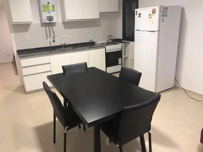 a kitchen with a black table and chairs and a refrigerator at COMPLEJO AYRES DE MAYU SUMAJ in Villa Carlos Paz