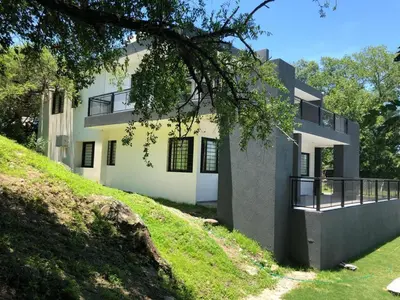 a large white building on a hill with a yard at COMPLEJO AYRES DE MAYU SUMAJ in Villa Carlos Paz
