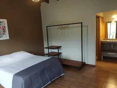a bedroom with a bed and a bathroom with a sink at CABAÑAS EXCLUSIVAS LAS ROSAS - CORDOBA in Villa de Las Rosas