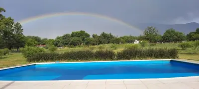 a rainbow over a blue swimming pool with a rainbow at CABAÑAS EXCLUSIVAS LAS ROSAS - CORDOBA in Villa de Las Rosas