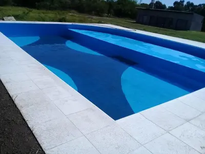 a large blue swimming pool in a yard at CABAÑAS EXCLUSIVAS LAS ROSAS - CORDOBA in Villa de Las Rosas