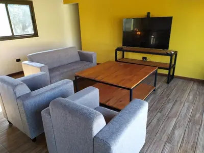 a living room with a couch and chairs and a tv at CABAÑAS EXCLUSIVAS LAS ROSAS - CORDOBA in Villa de Las Rosas