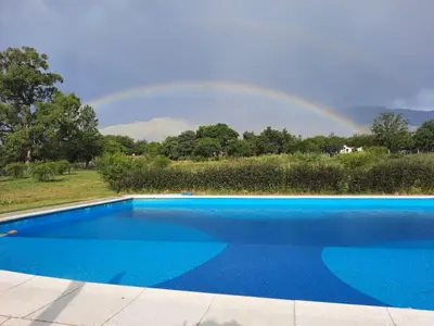 a rainbow over a blue swimming pool with a rainbow at CABAÑAS EXCLUSIVAS LAS ROSAS - CORDOBA in Villa de Las Rosas