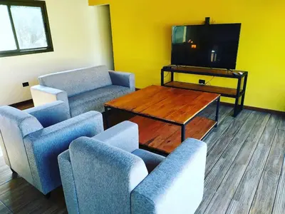 a living room with chairs and a table and a tv at CABAÑAS EXCLUSIVAS LAS ROSAS - CORDOBA in Villa de Las Rosas