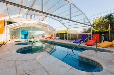 a swimming pool with colorful chairs and a house at Gran Turín Hotel Boutique parque,arte y tecnología in Villa Carlos Paz