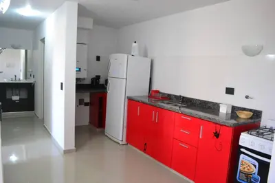 a kitchen with red cabinets and a white refrigerator at Dto con pileta en Carlos Paz 33! in Villa Carlos Paz