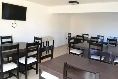 a dining room with tables and chairs and a flat screen tv at Dto con pileta en Carlos Paz 33! in Villa Carlos Paz