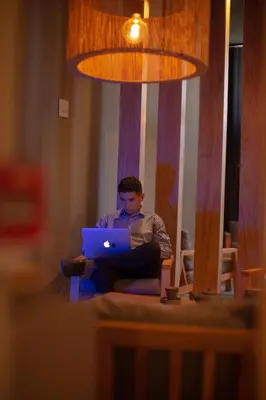 a boy sitting in a chair using a laptop computer at ÑU Posta Urbana Hotel Boutique in Cordoba