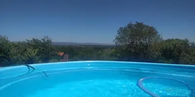 a large blue swimming pool with trees in the background at Cabaña Las liebres in San Roque