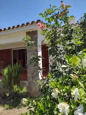 a house with a stone pillar and flowers in front of it at Villa Coca -Los Jilgueros- in La Bolsa