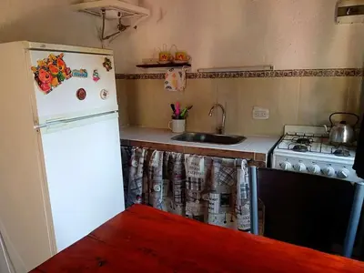 a kitchen with a white refrigerator and a sink at MONOAMBIENTES LOS SAUCES in Mina Clavero