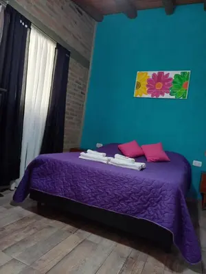 a purple bed in a room with a blue wall at MONOAMBIENTES LOS SAUCES in Mina Clavero