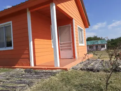 a red house with a porch with a door at La Nubia Cabañas in Conlara