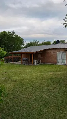 a brick house with a lawn in front of it at Casa LA OCASIÓN in Los Reartes