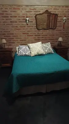 a bedroom with a bed with green sheets and pillows at Casa LA OCASIÓN in Los Reartes