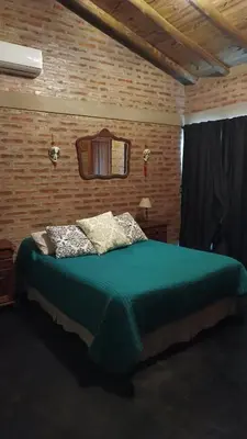 a bedroom with a green bed in a brick wall at Casa LA OCASIÓN in Los Reartes