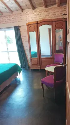a room with a bed and a table and windows at Casa LA OCASIÓN in Los Reartes