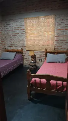 a bedroom with two beds and a brick wall at Casa LA OCASIÓN in Los Reartes