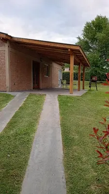 a building with a covered walkway in the grass at Casa LA OCASIÓN in Los Reartes
