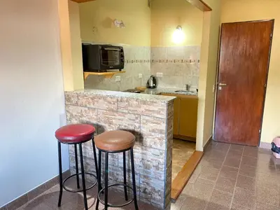 a kitchen with two stools and a counter with a microwave at Departamentos LOS CEDROS in Mina Clavero