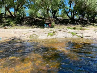 a stream of water with rocks and trees in the background at Departamentos LOS CEDROS in Mina Clavero