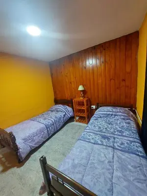 a bedroom with two beds and a table with a lamp at Departamentos la Familia NONO in Nono