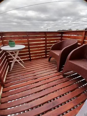 a wooden deck with two chairs and a table at Complejo SARA HOUSE in Santa Rosa de Calamuchita