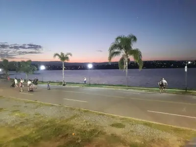 a group of people walking down a street with palm trees at Cabañas San Gabriel Carlos Paz in Villa Carlos Paz