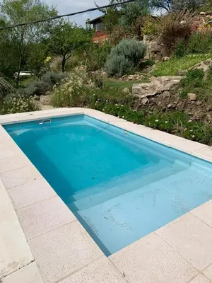 a large blue swimming pool in a yard at Cabañas Namaskar in Villa Serranita