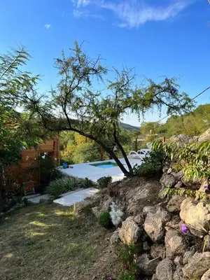 a stone wall with a tree in a yard at Cabañas Namaskar in Villa Serranita