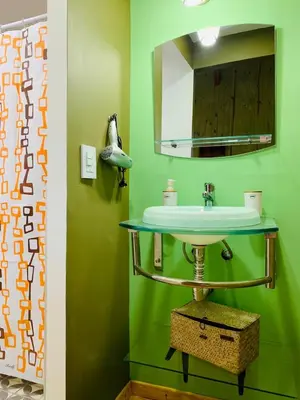 a green bathroom with a sink and a mirror at Cabañas Namaskar in Villa Serranita