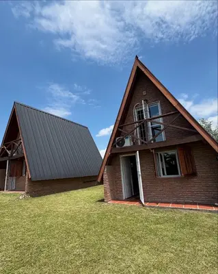 a house with a gambrel roof on a grass field at Cabañas Sueño Dorado in Potrero de Garay