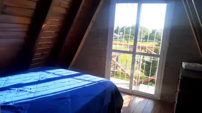 a bedroom with a bed and a large window at Cabañas Sueño Dorado in Potrero de Garay