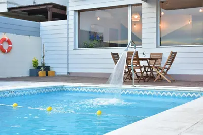 a swimming pool with a fountain in front of a house at Alamo Hotel in Villa Carlos Paz