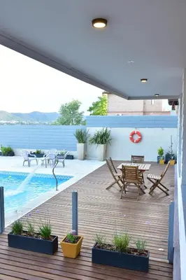 a deck with chairs and a table and a pool at Alamo Hotel in Villa Carlos Paz
