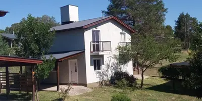 a white house with a porch and a balcony at Duplex Alto El Espinillo in Villa General Belgrano