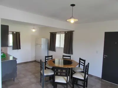a dining room with a table and chairs and a refrigerator at Duplex Alto El Espinillo in Villa General Belgrano
