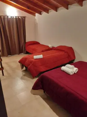 two beds in a room with red sheets and towels at Duplex Alto El Espinillo in Villa General Belgrano