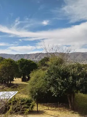 a field with trees and mountains in the background at Duplex Alto El Espinillo in Villa General Belgrano