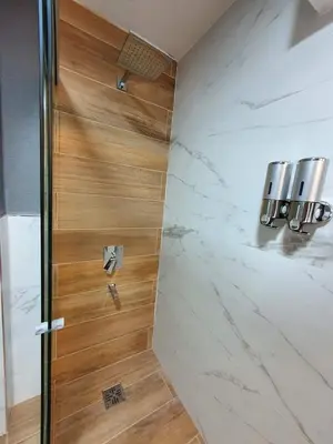 a shower with a wooden door in a bathroom at Alojamiento Maria :-) in Cordoba