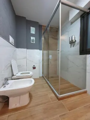 a bathroom with a toilet and a glass shower at Alojamiento Maria :-) in Cordoba