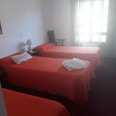 a bedroom with two beds with red sheets and a window at Hotel Andino in Villa Carlos Paz