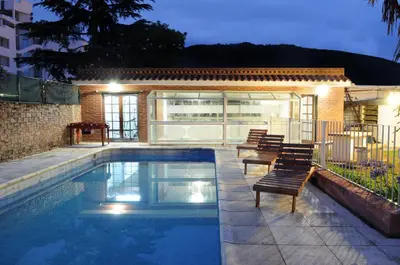 a swimming pool with chairs next to a building at Hotel Andino in Villa Carlos Paz