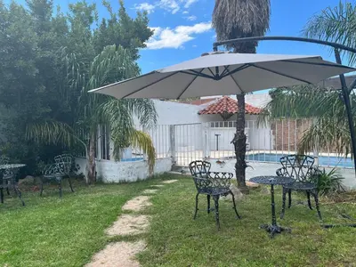a table and chairs under an umbrella next to a pool at Hotel Andino in Villa Carlos Paz