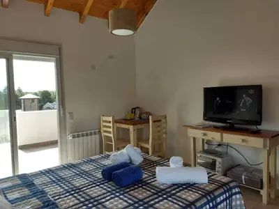 a bedroom with a bed with blue pillows and a television at Mirador Suite in Villa General Belgrano